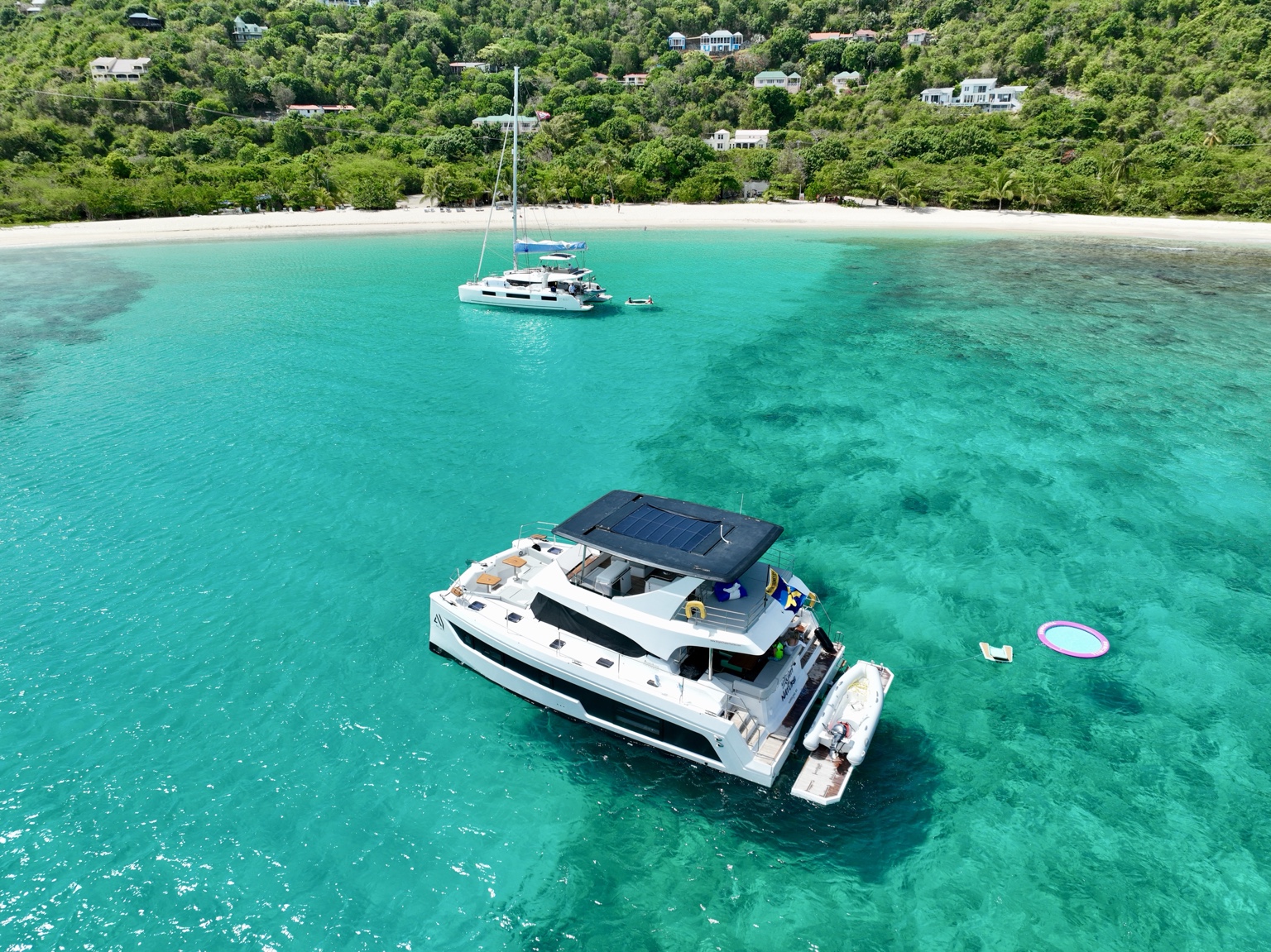 Yachti By Nature luxury power catamaran anchored off a British Virgin Islands beach